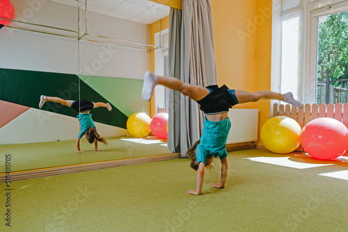 Little girl doing handstand with twine in sport gym photo