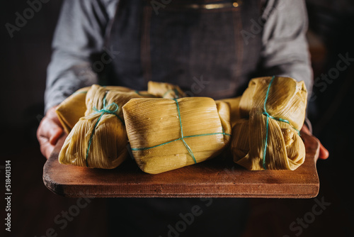 woman's hands holding chilean homemade humitas. Ground corn mix wrapped in corn husks and boiled photo