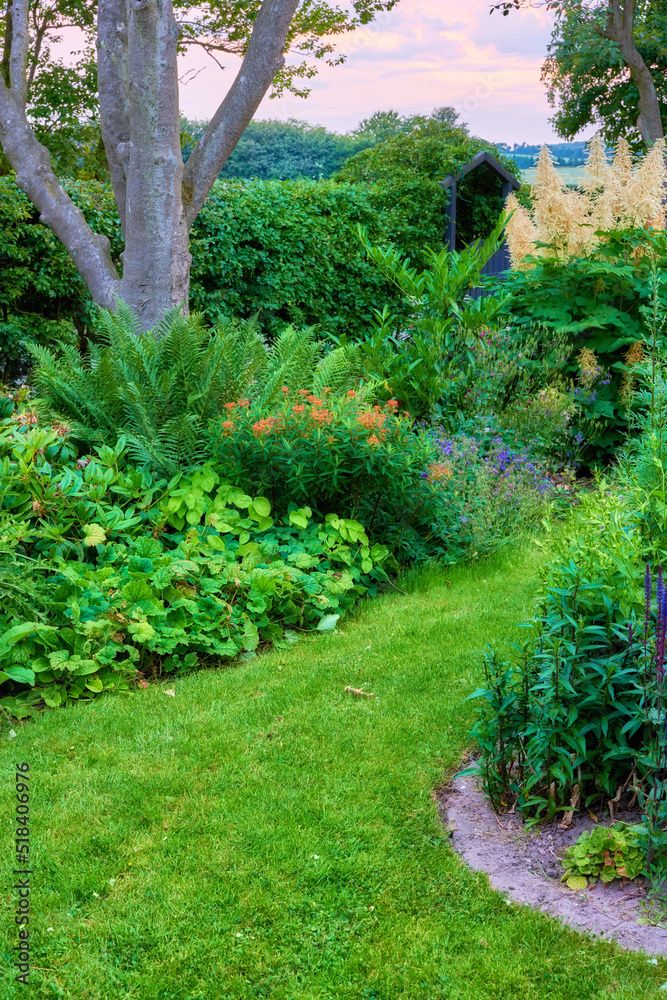 Vibrant lush green nature in a peaceful, calm garden on a sunny day. Many trees, bushes and flowers growing in serene harmony. Calming views of bright lawn and floral blossoms in a park