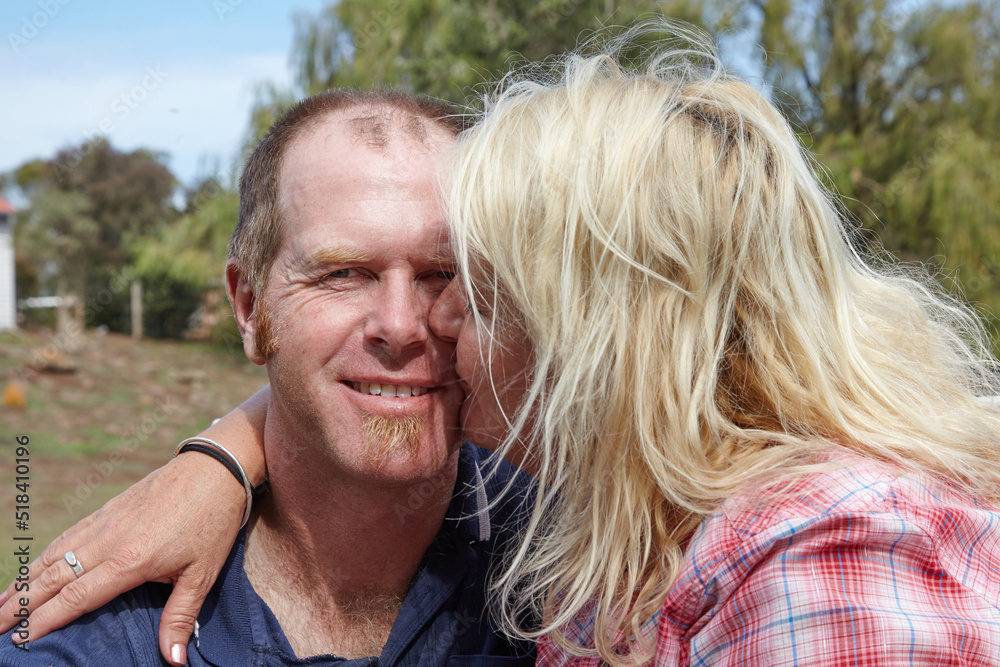 Couple embrace and wife kisses husband on cheek Couple embrace and wife kisses husband on cheek