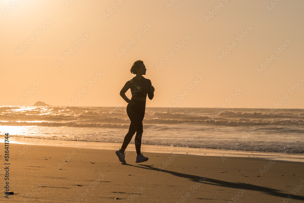 Female runner jogging during the summer morning on sandy beach