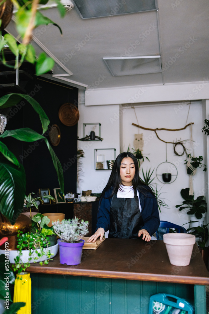 Female florist tidying up workspace before starting working day Female florist tidying up workspace before starting working day