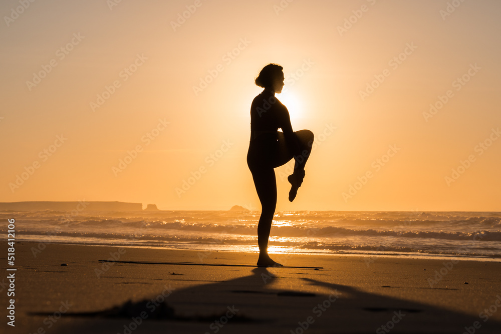 Silhouette of the girl practicing meditate and yoga near the sea in the morning