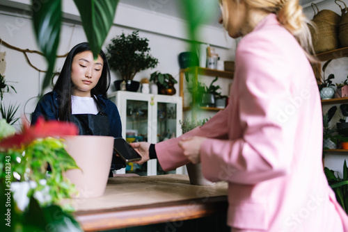Female worker receiving defrayment in floral store from visitor
