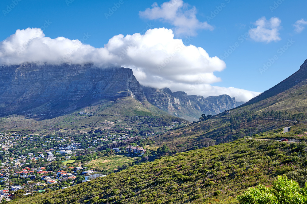 Panorama of a city near mountains in South Africa. Landscape of Cape Town suburbs beneath Table Mountain and a cloudy blue sky. Beautiful greenery and scenic nature near a rural town with copy space.