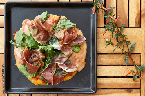 prosciutto and vegetable pizza served on a wooden table