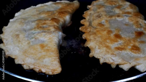 Pasties filling meat or cheburek fried in cooking oil in hot frying pan. photo