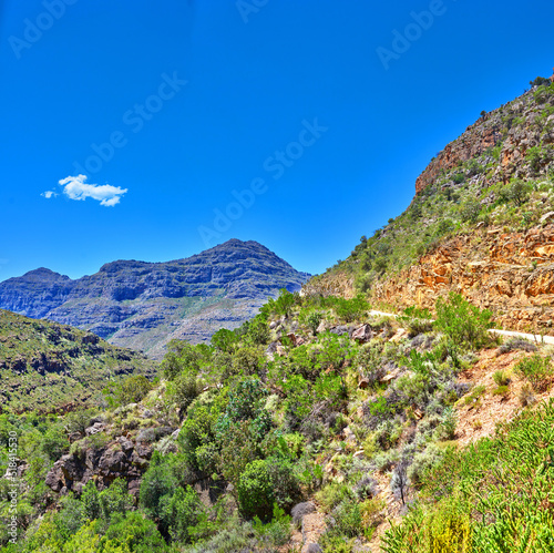 Beautiful landscape of mountains covered in lush green plants with a blue sky on a summer day. Peaceful and scenic view of a peak or hills surrounded by nature outdoors on a spring afternoon