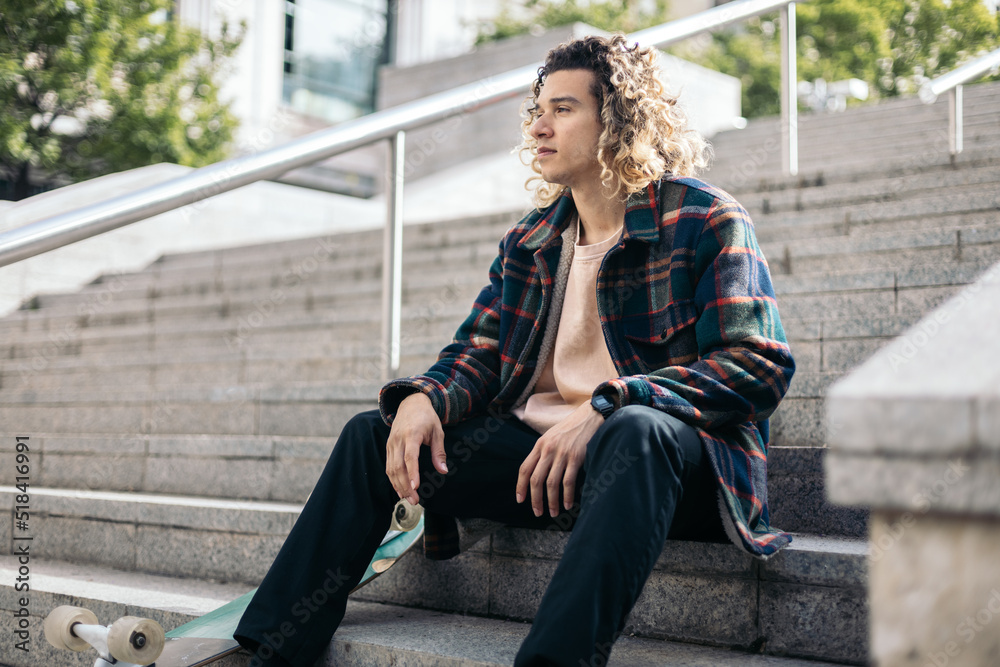 Skateboarder resting sitting on some steps Skateboarder resting sitting on some steps