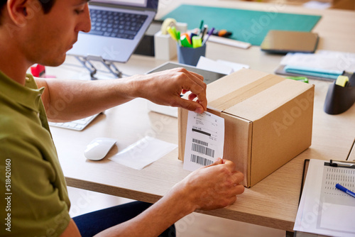 Post office worker attaching address paper to parcel
