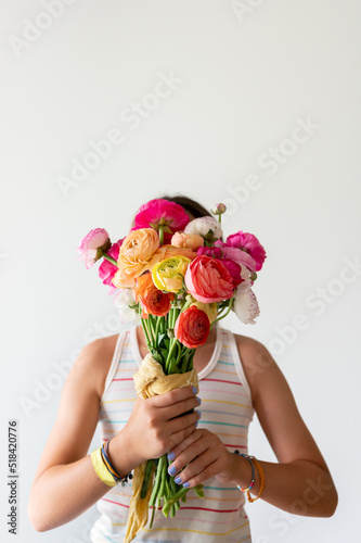 Girl holding up ranunculus bouquet in front of her face