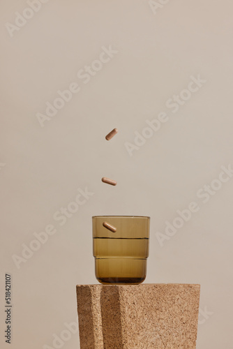 beauty product still life of supplement pills and glass of water photo