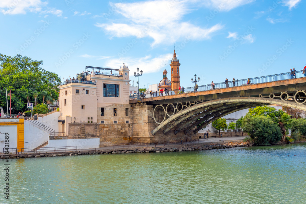 The Triana district of Seville, Spain with the Capilla del Carmen church on the left near the Puente de Isabel bridge over the Guadalquivir River.