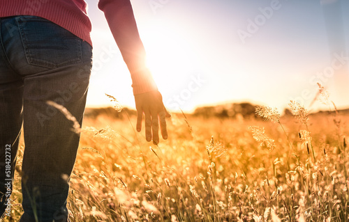 Female walking on open field at sunset. Feeling at peace in nature concept. 