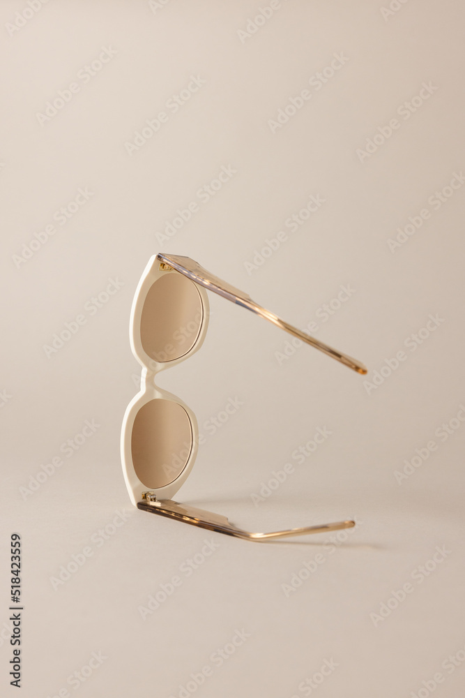 © Nicole Mason/Stocksy - pair of sunglasses on light tan background