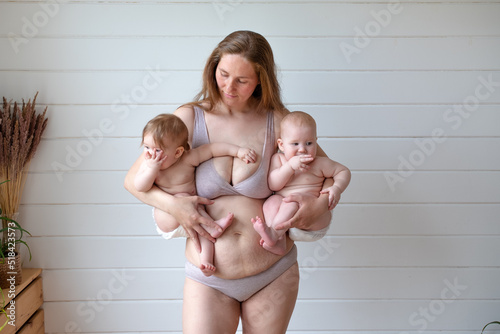 woman in lingerie posing holding two babies photo