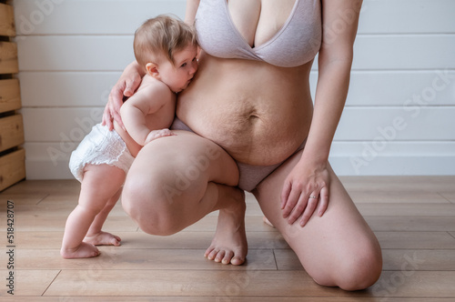 infant kisses mother stretch marks belly