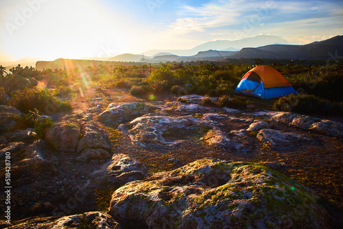 camping tent at sunset with bright sun in the horizont and stone bowls with mountains in the background in zimapan hidalgo  photo