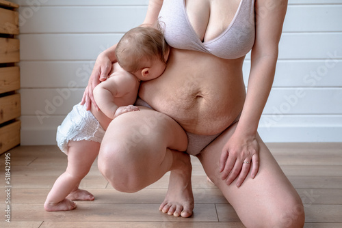infant kisses mother stretch marks belly photo
