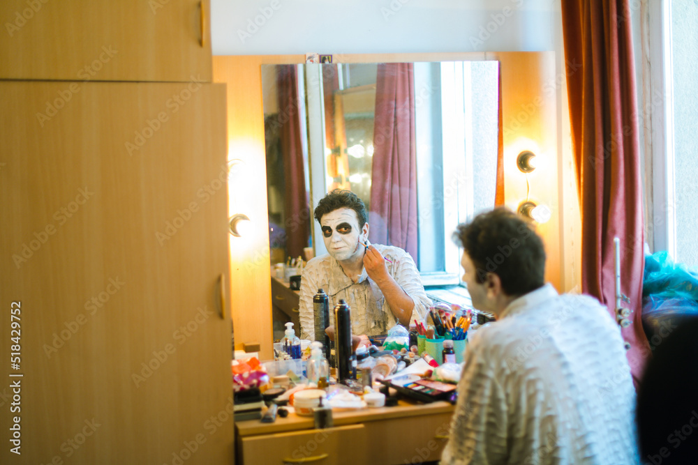 Actor  in front of a mirror makes make-up himself