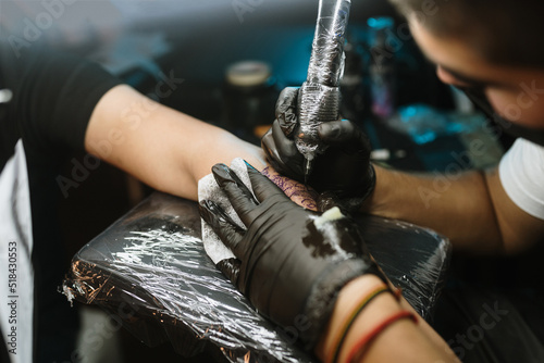 Close-up of tattoer using tattoo machine on an arm photo