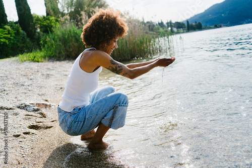 Woman crouching by the water photo