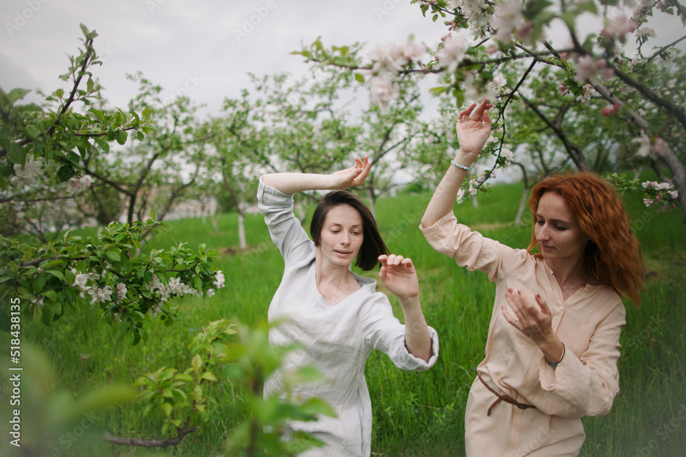 two women contemporary dancers dancing in a blossom garden two women contemporary dancers dancing in a blossom garden