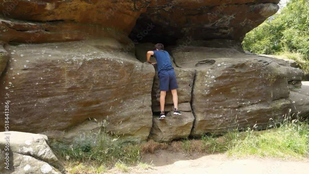 Young boy climbing and jumping on the rocks at Brimham Rocks, once known as Brimham Crags in North Yorkshire, surrounded by woodland in the UK. Young boy climbing and jumping on the rocks at Brimham Rocks, once known as Brimham Crags in North Yorkshire, surrounded by woodland in the UK.