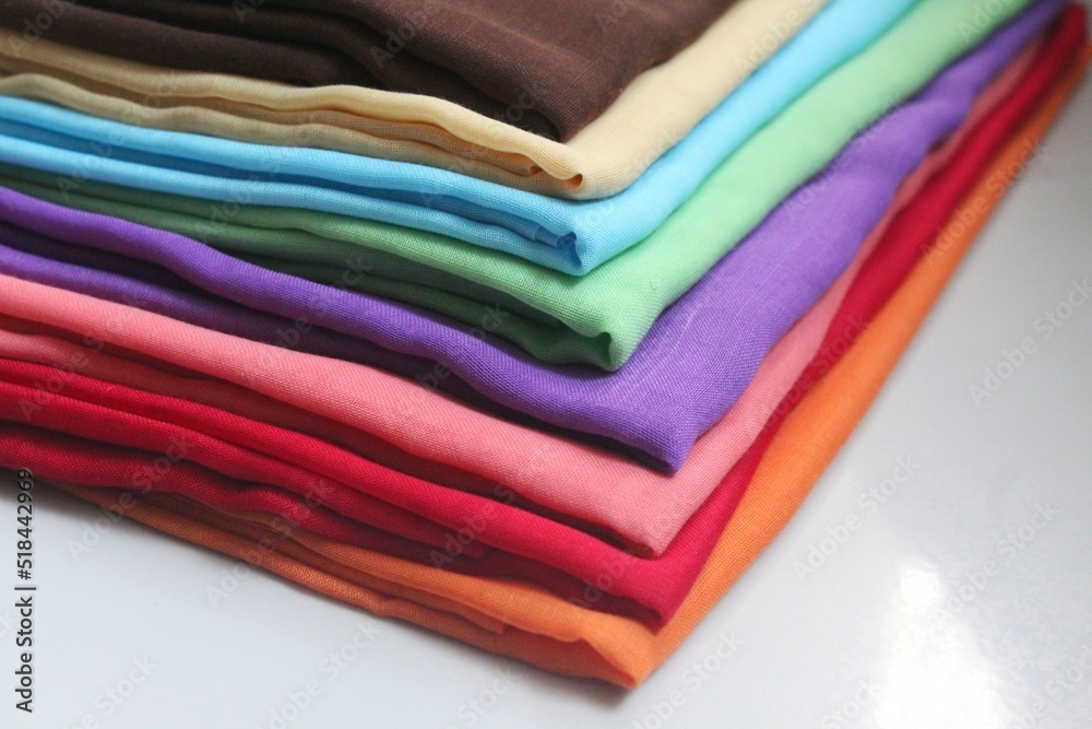 pile of rectangular hijabs of various colors on the white floor