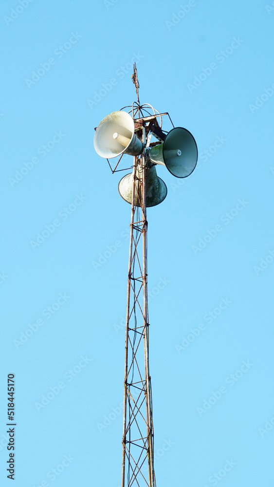 Mosque loudspeaker on top of the iron minaret. Blue sky background. Focus selected Mosque loudspeaker on top of the iron minaret. Blue sky background. Focus selected