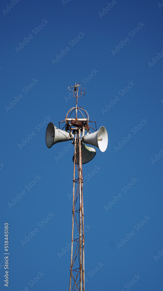 Mosque loudspeaker on top of the iron minaret. Blue sky background. Focus selected Mosque loudspeaker on top of the iron minaret. Blue sky background. Focus selected