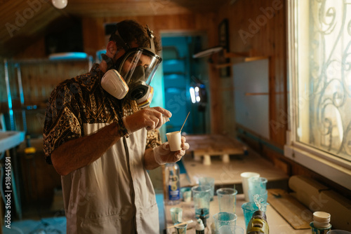 Serious man in respirator mixing resin in cup photo