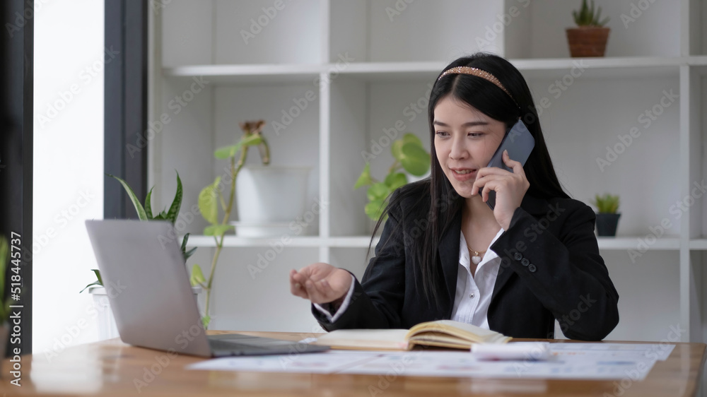 Asian businesswoman talking on the phone with customer in the office. Asian businesswoman talking on the phone with customer in the office.