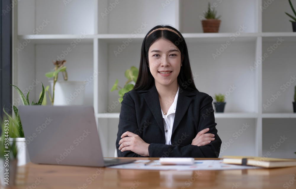 Charming Asian woman working at the office using a laptop Looking at the camera. Charming Asian woman working at the office using a laptop Looking at the camera.