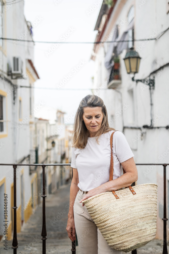 mature woman with a wicker basket in a village in Portugal mature woman with a wicker basket in a village in Portugal