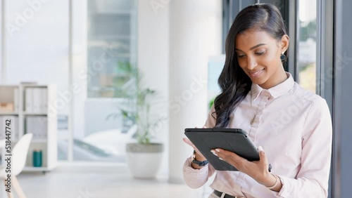 Business woman responding to an email on a digital tablet in a modern office. Young female analyzing or taking stock on a smart device. Confident manager staying organized with administration