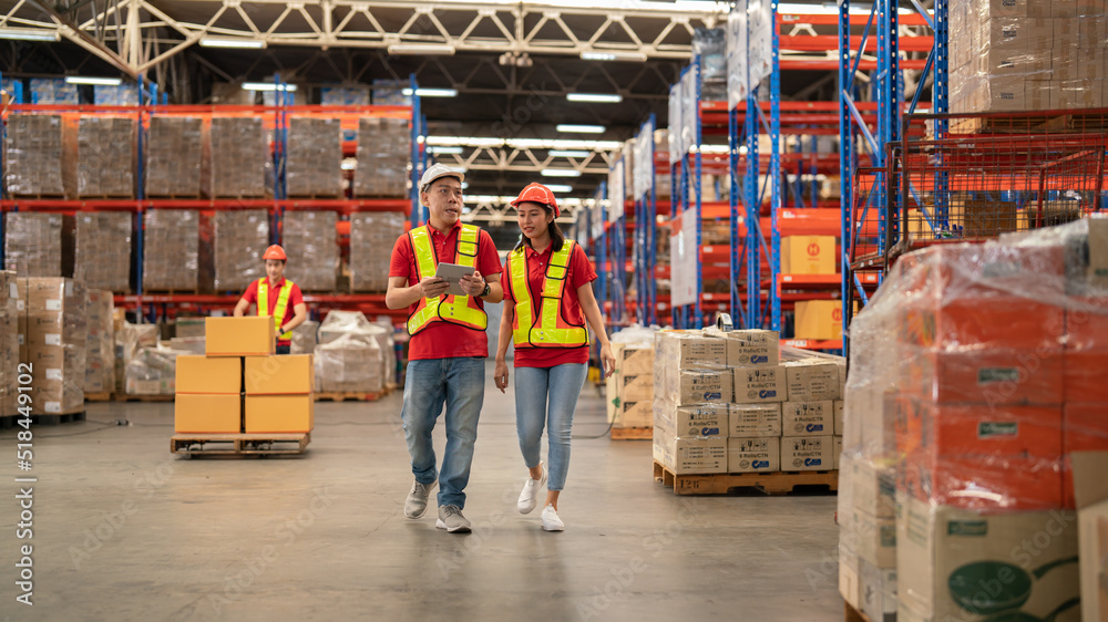 Male and female warehouse workers Working at a distribution center, standing, talking, at a large warehouse. New arrivals of additional items in the warehouse department. Employees who organize the di Male and female warehouse workers Working at a distribution center, standing, talking, at a large warehouse. New arrivals of additional items in the warehouse department. Employees who organize the di