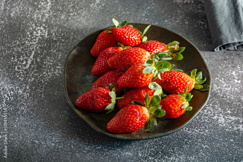 red fresh and delicious strawberries on a dark plate. dark food photography