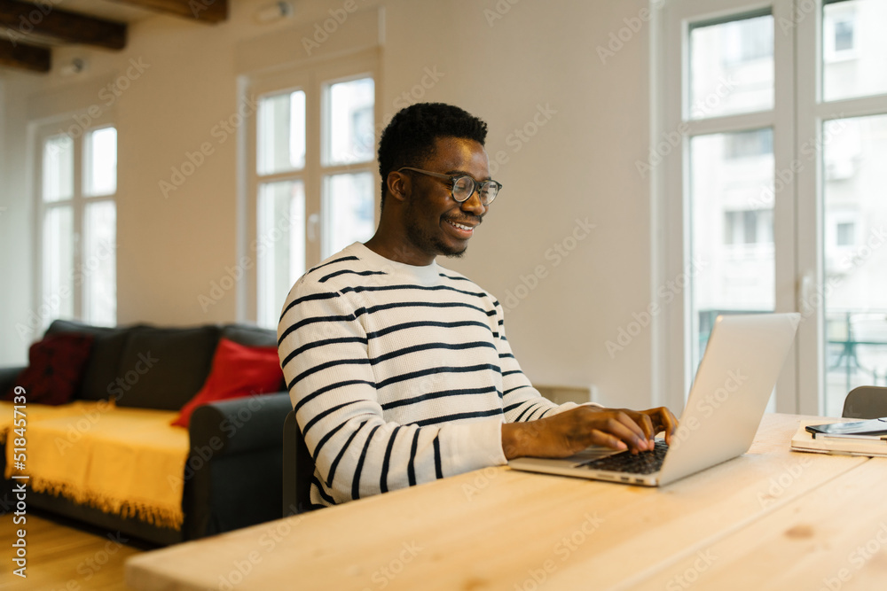 Smiling man having video call via computer indoors Smiling man having video call via computer indoors