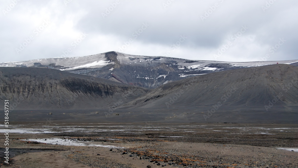 Snow covered mountains above a volcanic landscape at Telefon Bay, Deception Island, Antarctica