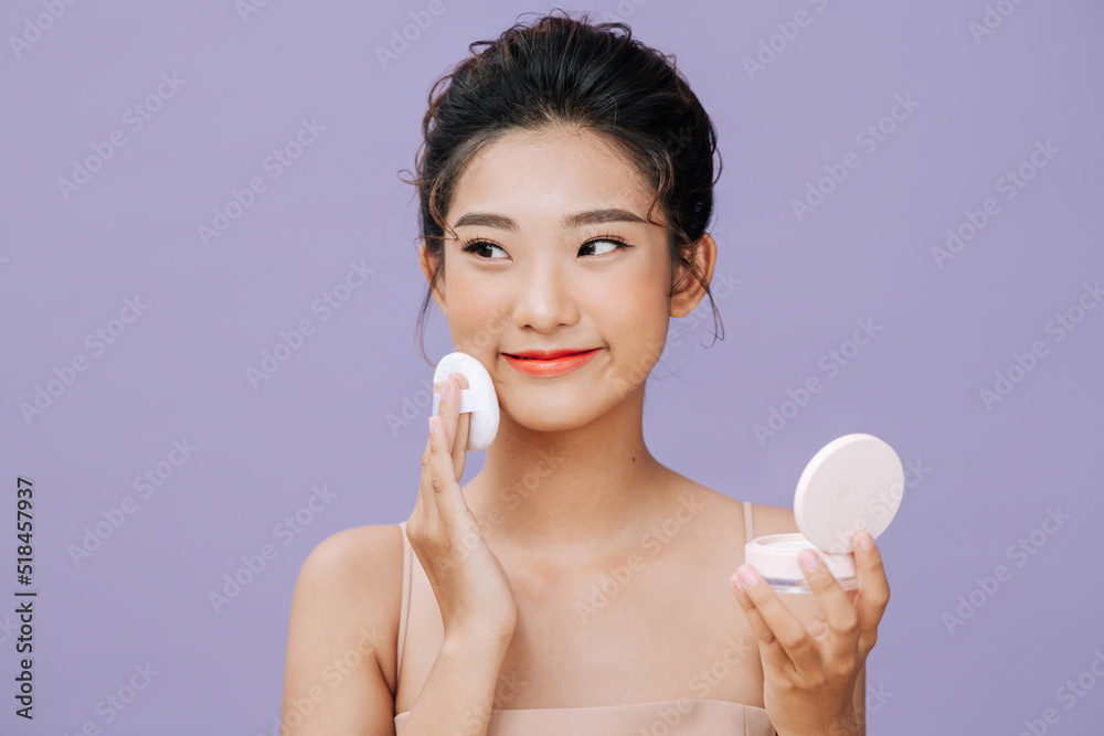 Beautiful young woman applying face powder with puff applicator Beautiful young woman applying face powder with puff applicator