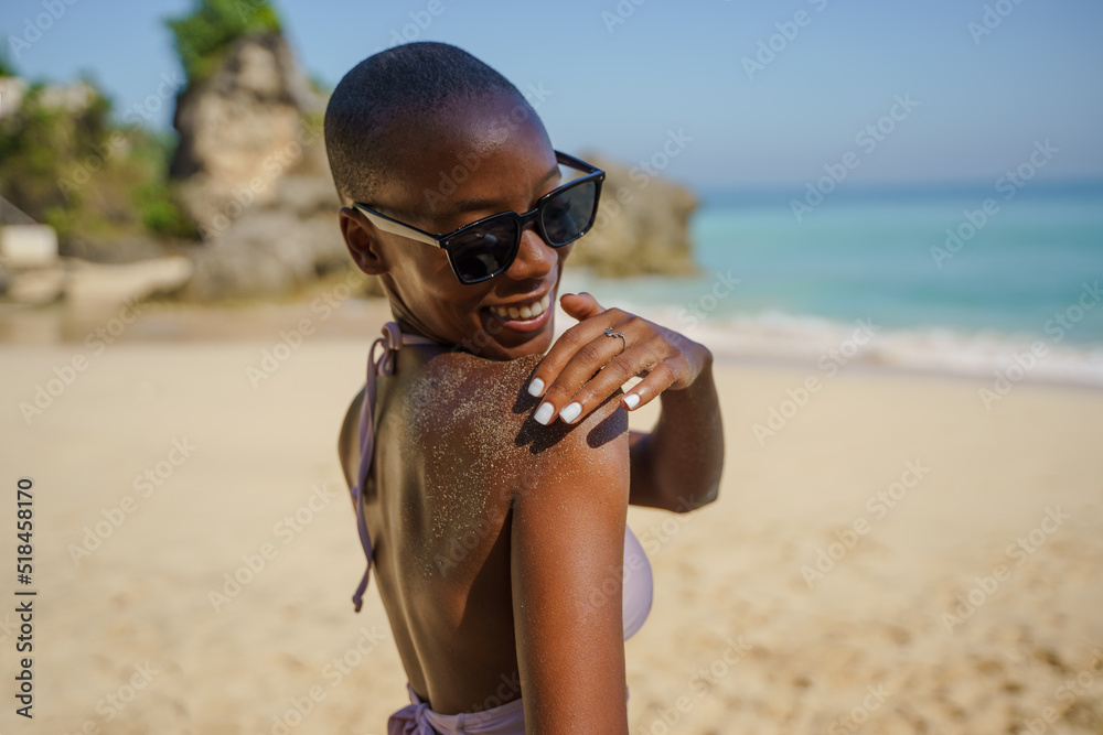 Happy African American woman brushing off sand from body at beach Happy African American woman brushing off sand from body at beach