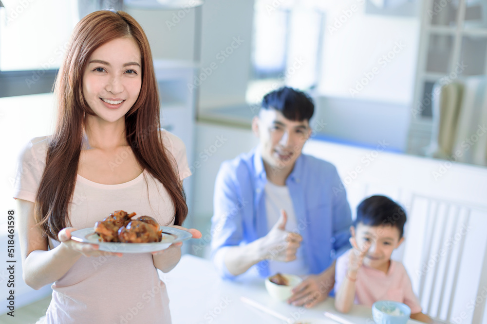 Mother showing tasty food and father showing thumbs up. Happy Asian  family having dinner at home
