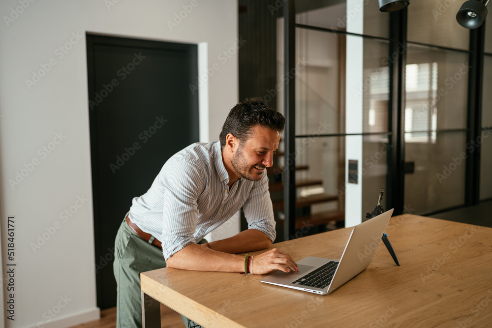 Cheerful businessman using netbook in dining room Cheerful businessman using netbook in dining room