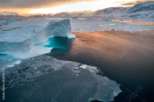 Beautiful Greenland winter iceberg, seal hunters' boats in new sea ice photo