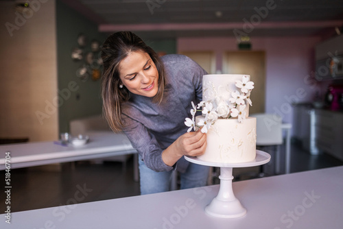 young pastry chef decorating a beautiful cake in her pastry shop