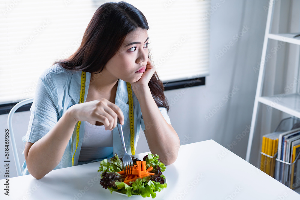 Asian women aiming to lose weight but tired of eating vegetable salad.