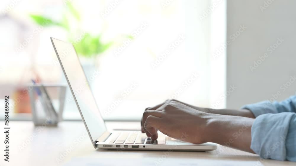 Side View of Young African Man Typing on Laptop Keyboard Side View of Young African Man Typing on Laptop Keyboard