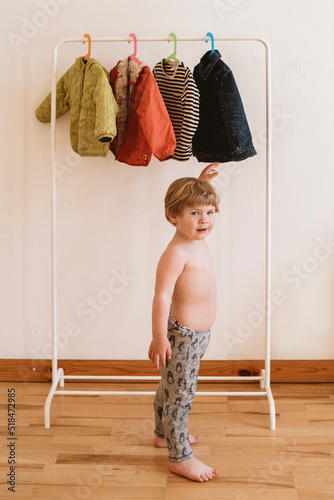 Toddler chooses clothes hanging on a rail