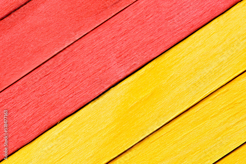 Bright yellow and red painted boards arranged diagonally. Close up wooden textured background. Textured straight planks in red and yellow.